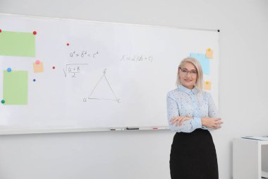 Modern sınıfta beyaz tahtanın yanında olgun bir öğretmen. Metin için boşluk