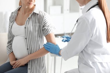 Doktor, hastanede hamile kadına iğne yapıyor. Yakın çekim. Aşılama kavramı