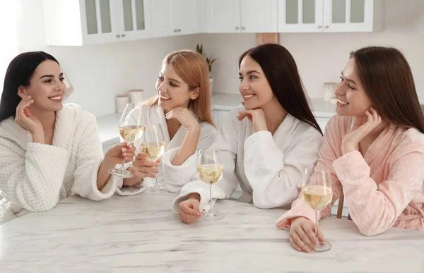 Beautiful young ladies with glasses of wine in kitchen. Women\'s Day
