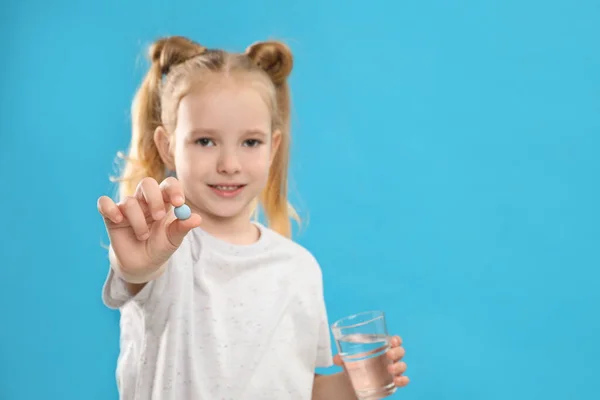 Κοριτσάκι Βιταμίνη Χάπι Και Ένα Ποτήρι Νερό Μπλε Φόντο Επικεντρώσου — Φωτογραφία Αρχείου