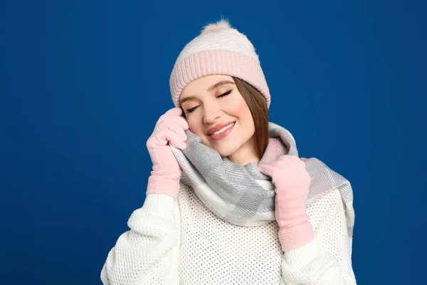 暖かいセーター スカーフ 帽子を青い背景に身に着けている若い女性 冬の季節 — ストック写真
