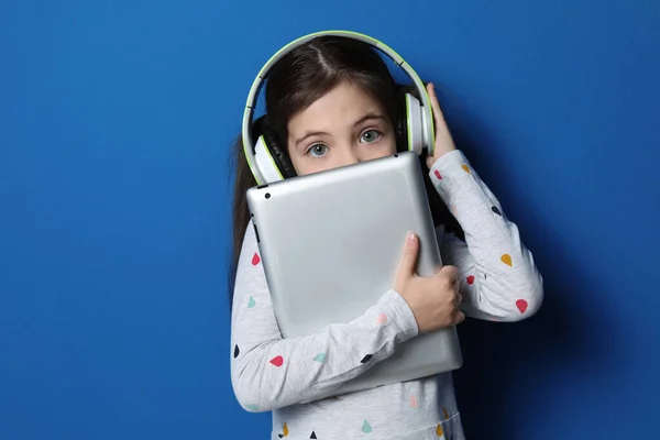 Cute Little Girl Słuchawkami Tabletem Słuchając Audiobook Niebieskim Tle — Zdjęcie stockowe