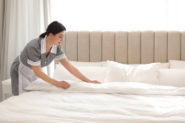 Otel odasında yatak yapma genç Oda hizmetçisi. Metin için yer