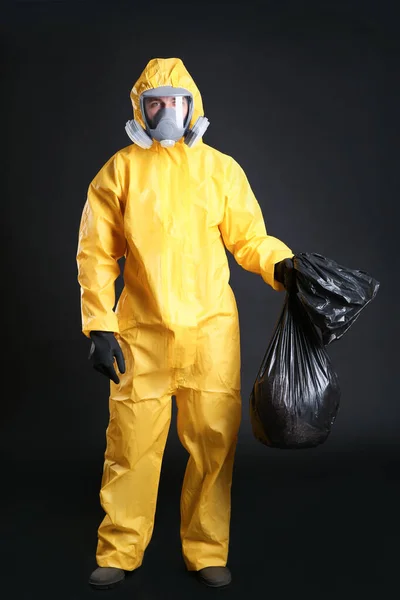 黒の背景にゴミ袋を持っている化学保護スーツの男 ウイルス研究 — ストック写真