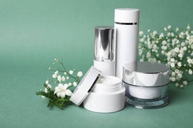 Mavi-yeşil arka planda lüks kozmetik ürünleri ve bitkiler
