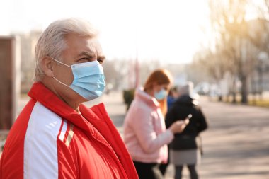 Şehir caddesinde tıbbi maskeli kıdemli bir adam. Virüs koruması