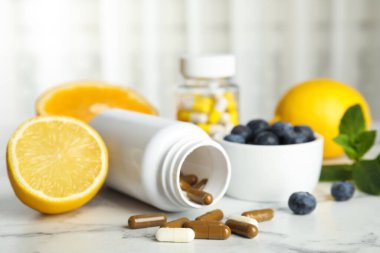 Vitamin hapları, yabanmersini ve limonlu beyaz mermer masa.