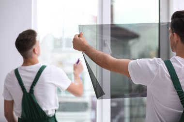 Profesyonel işçiler pencereyi folyoyla boyuyor.