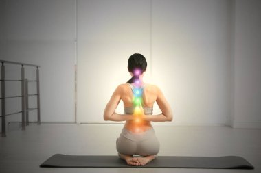 Çakra puanı alan genç bir kadın stüdyoda, arka planda yoga yapıyor. İyileştirme enerjisi 
