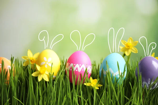 色彩艳丽的复活节彩蛋 长着可爱的小兔子耳朵 绿色的草地上开满了花朵 — 图库照片