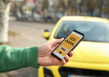 Şehir caddesinde akıllı telefondan taksi çağıran adam, yakın plan.