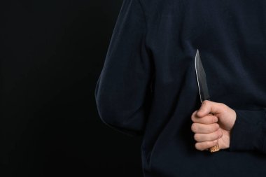 Siyah arka planda arkasından bıçaklı bir adam, yakın plan. Tehlikeli suçlu.