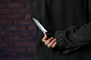 Sırtından bıçaklanan adam tuğla duvarın yanında, yakın plan. Tehlikeli suçlu.