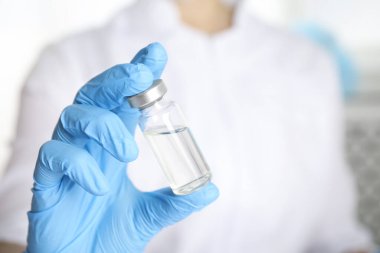 Doktorun elinde ilaç şişesi var, yakın plan. Aşılama ve aşılama