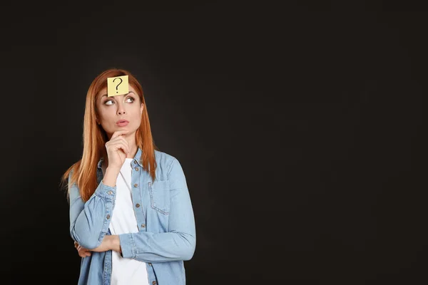 Umsichtige Frau Mit Fragezeichen Aufkleber Auf Der Stirn Vor Schwarzem — Stockfoto