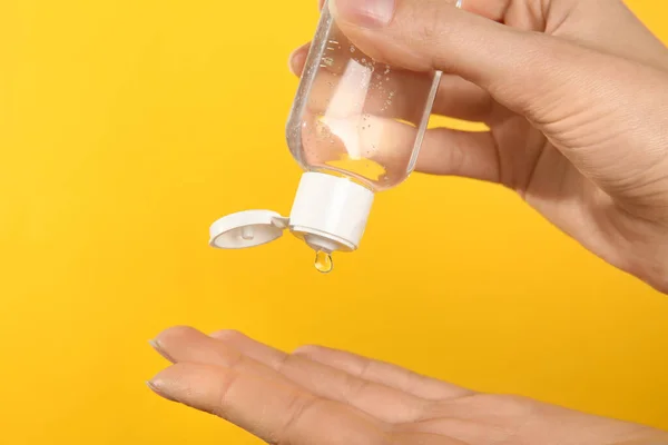 Mujer Aplicando Gel Antiséptico Sobre Fondo Amarillo Primer Plano —  Fotos de Stock