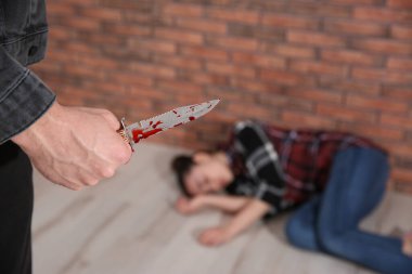 Kanlı bıçaklı bir adam ve yerde yatan kurbanı, yakın plan. Tehlikeli suçlu.