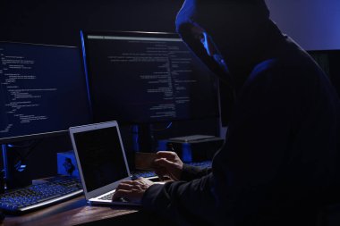 Hacker with computers and credit card in dark room. Cyber crime clipart