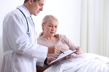 Doktor hastane koğuşundaki hastasını ziyaret ediyor.