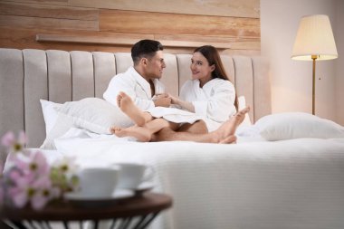 Bornozlu mutlu çift evde yatakta dinleniyor.