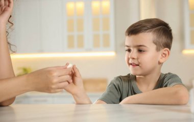 Afro-Amerikalı kadın mutfaktaki küçük çocuğa vitamin hapı veriyor.