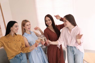 Evde şampanya bardaklarını tokuşturan güzel genç bayanlar. Kadınlar Günü