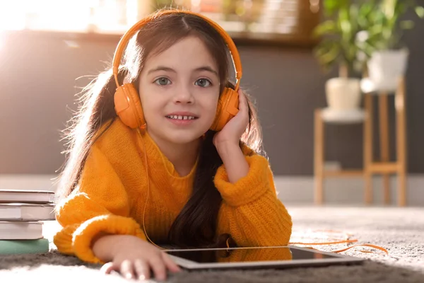 可爱的小女孩 家里戴着耳机 穿着橙色针织毛衣 — 图库照片