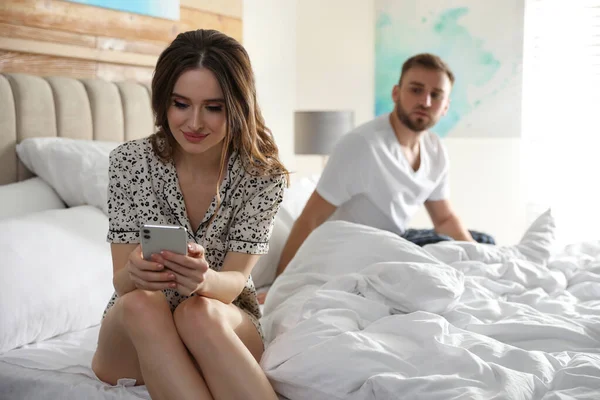 年轻人在家里偷看女朋友的智能手机 嫉妒的关系 — 图库照片