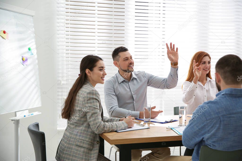 Man raising hand to ask question at business training in conference room