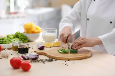 Kadın aşçı mutfak masasında yemek pişiriyor.