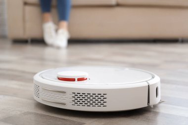 Robot elektrik süpürgesi evde çalışırken dinlenen bir kadın.