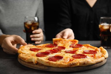 Gri masada lezzetli biberli pizza yiyen kadınlar, yakın plan.