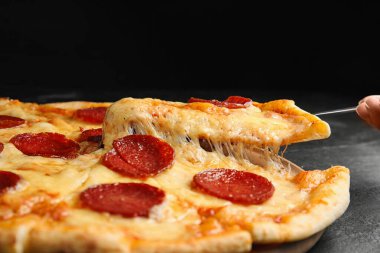 Siyah masadaki lezzetli biberli pizzayı alıyorum, yakın plan.