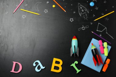 Parlak oyuncak roketler, okul malzemeleri ve karatahtadaki çizimler, düz konum. Metin için boşluk