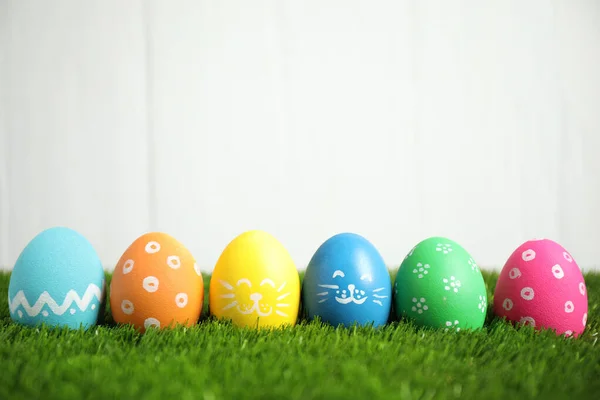五彩缤纷的复活节彩蛋在绿草上 衬托着白色背景 案文的篇幅 — 图库照片