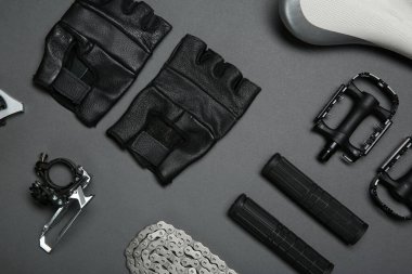 Gri arka planda farklı bisiklet parçaları ve eldivenler var.