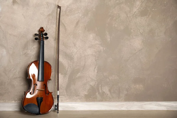 Classic violin and bow near beige wall. Space for text