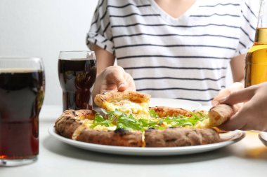 İnsanlar beyaz masada lezzetli peynirli pizza yiyorlar, yakın plan.