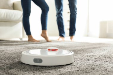 Evde robot süpürge kullanan çift.