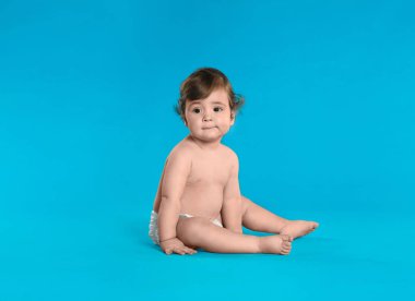 Açık mavi arka planda bebek bezi takmış şirin bir bebek. Metin için boşluk