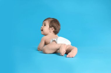 Açık mavi arka planda bebek bezi takmış şirin bir bebek.
