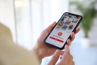 MYKOLAIV, UKRAINE - 16 Mart 2020: Pinterest uygulamalı iPhone 11 'i kapalı alanda tutan kadın, yakın plan