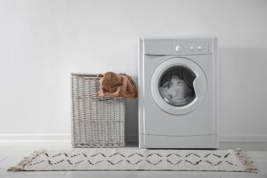 Modern çamaşır makinesi ve çamaşır sepeti beyaz duvarın yanında. Banyo içi.
