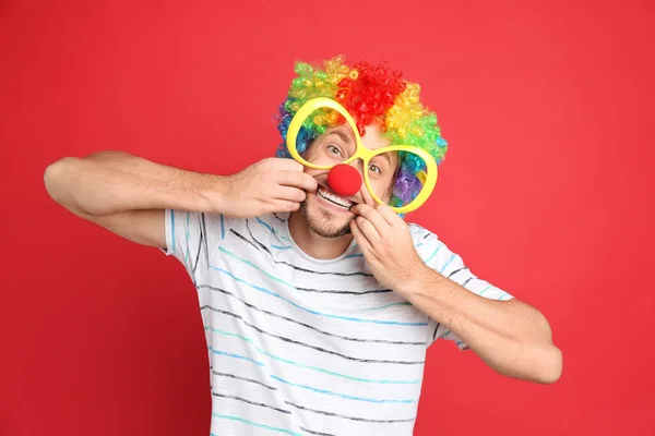 Lustiger Mann Mit Großer Brille Regenbogenperücke Und Clownsnase Auf Rotem — Stockfoto