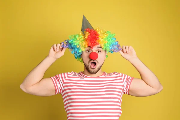 多愁善感的年轻人 头戴派对帽 头戴小丑假发 背景是黄色的 四月愚人节 — 图库照片