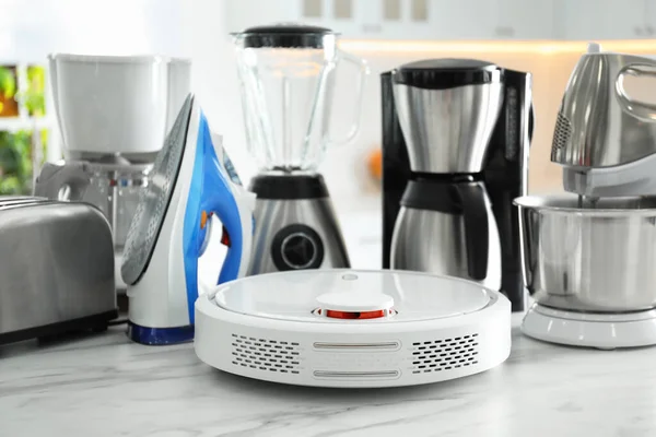 Set of modern home appliances in kitchen, focus on robotic vacuum cleaner
