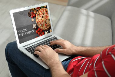 Karantina sırasında dizüstü bilgisayarı yemek siparişi için kullanan adam, yakın plan. Teslimat servisi