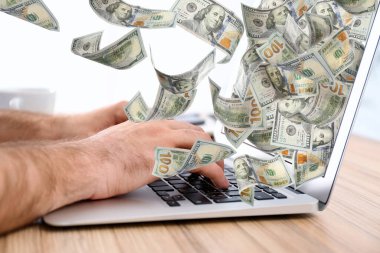 Modern dizüstü bilgisayarı ve uçan dolar banknotları olan bir adam, yakın plan. İnsanlar çevrimiçi para kazanıyor