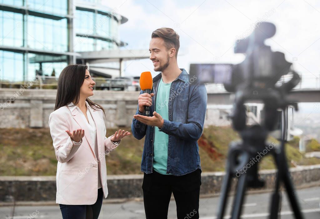 Young journalist interviewing businesswoman on city street