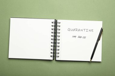 Yeşil arkaplandaki defter ve kalemi aç, üstten bak. Coronavirüs salgını sırasındaki karantina günleri sayılıyor
